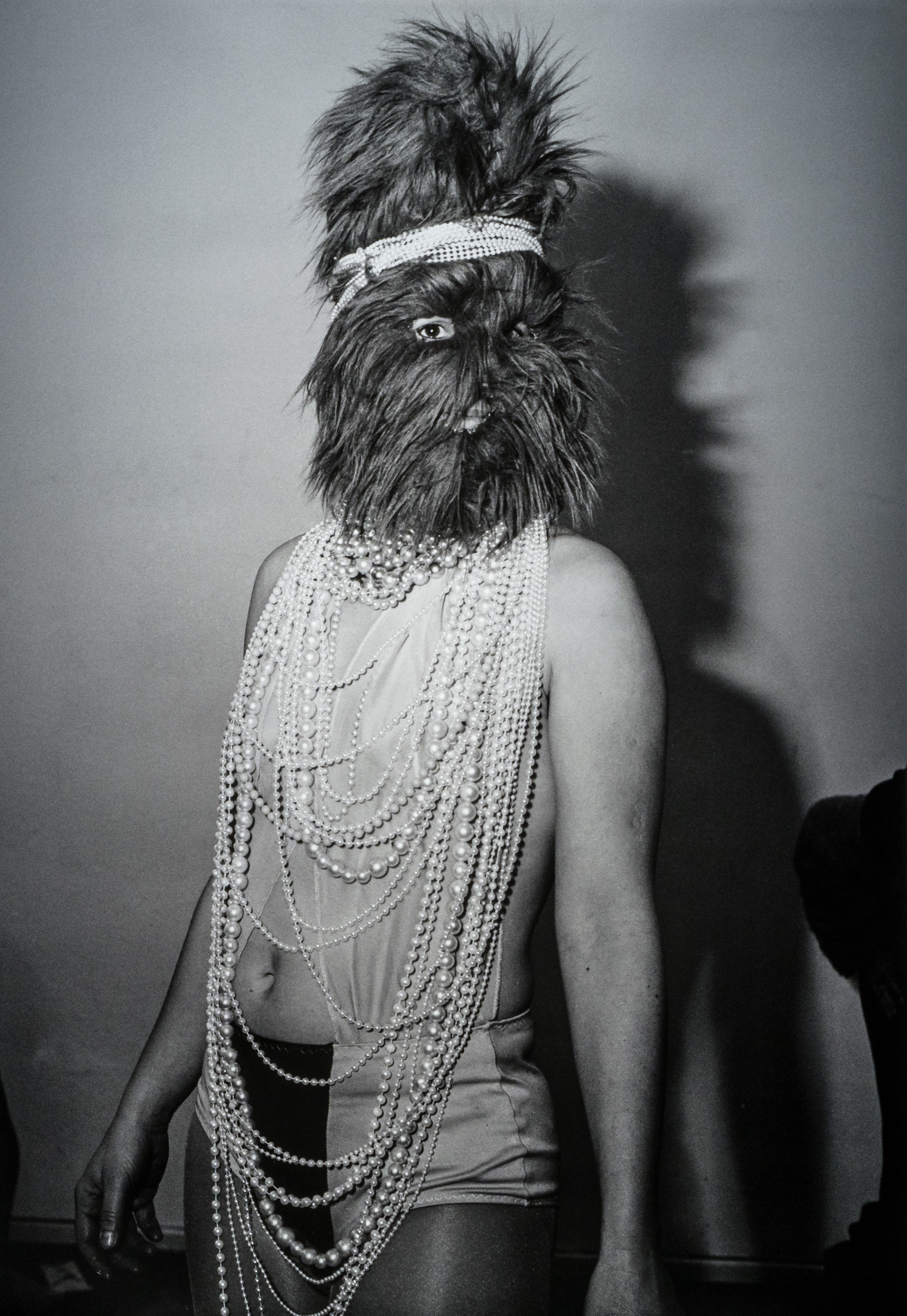 Woman dressed in pearls and a hairy face mask