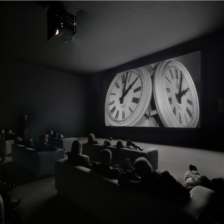 Biovisning med soffor av Christian Marclays film The Clock