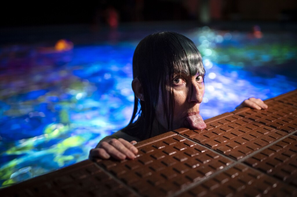 Artist Pipilotti Rist extends her tongue and rests it on the poolside